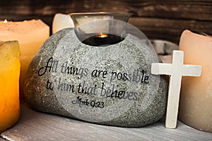 Stone with christian scripture with light candle cross