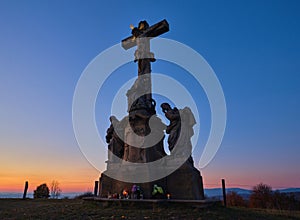 Stone christianity monument at the top of a hill at sunset