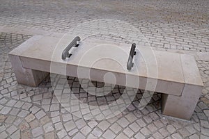 Stone city bench seat with center arm rests on hostile design prevents the homeless from laying down in town center