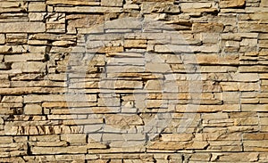 Stone cladding wall made of striped stacked slabs of natural brown rocks.