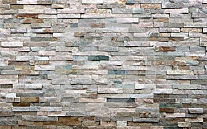 Stone cladding wall made of striped stacked slabs of natural multicolor rocks. Panels for exterior,