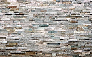 Stone cladding wall made of striped stacked slabs of natural multicolor rocks. Panels for exterior, photo