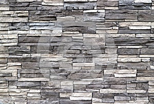 Stone cladding wall made of  striped stacked slabs of natural rocks. Colors are dark gray and white