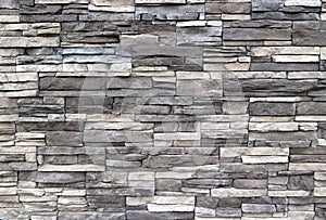 Stone cladding wall made of  striped stacked slabs of natural rocks. Colors are dark gray and white photo