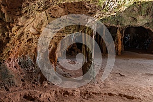 Stone columns in Quadiriki cave, Aruba. Multi-colored. Open cavern in background.