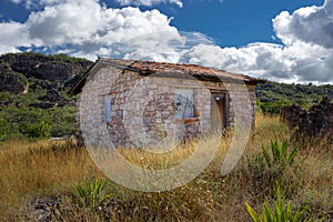 Stone country house in a field with a hill and cloudy sky as background photo