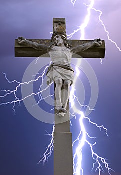 Stone cross with Jesus and sky with lightning