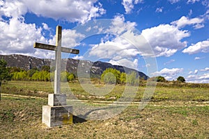 Stone cross on the mountain above clouds against blue sky