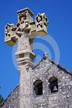 Stone cross set up in front of a medieval church.