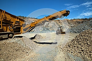 A stone crusher machine and a bulldozer in an open-type stone quarry