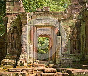 Stone doorway guarded by two warrior statues at Ta Prohm temple ruins, located in the Angkor Wat complex near Siem Reap, Cambodia.