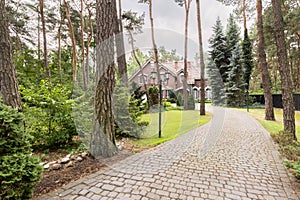 Stone driveway to english red brick residence in the forest