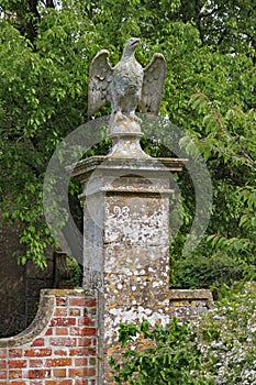 A stone eagle on a square plinth stands guard over an English country house