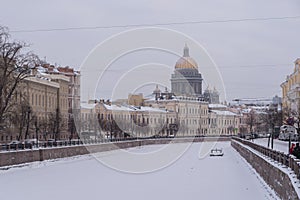 Stone embankments of Moyka River with scenic mansions and golden dome of St Isaac`s Cathedral on background