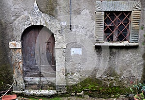 Stone entrance portal and wooden door of the entrance of an ancient house, no longer inhabited but suggestive, in Vergemoli.