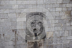 Stone face scuplture in stone wall water stream