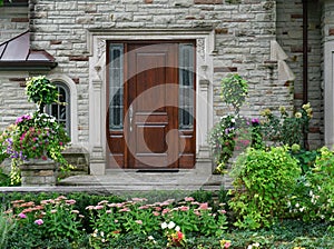 Stone faced house with flower garden and elegant wooden front door