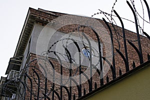 Stone fence with metal rods and barbed wire on top.