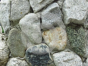 Stone fence. Wall made of grey rock  blocks. Stone wall cladding. Old stone wall wallpaper or background.