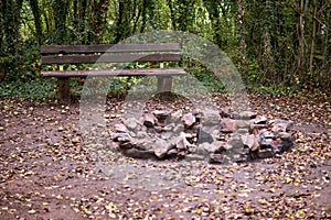 Stone fireplace photographed with a wooden bench in nature.