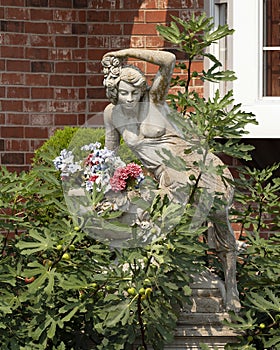 Stone flower pot with bare breasted beautiful woman sculpture in a garden in Bethany, Oklahoma.