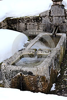 Stone fountain with freezing cold water in winter