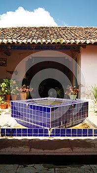 stone fountain, in old mexican house, latin america, with decorated tiles, roof tiles, surrounding vegetation