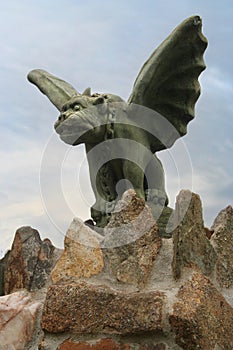 A stone gargoyle on a stone fence stands watch.