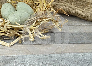 Stone Grey decoration eggs with straw on burlap over wooden background