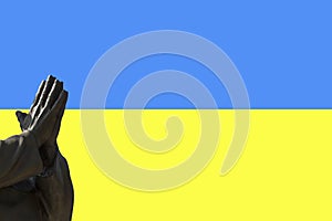 Stone Hands in Pray Gesture on the blue and yellow National flag of Ukraine
