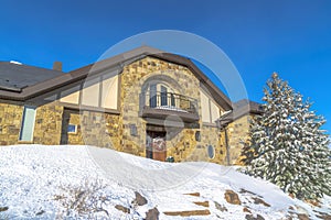 Stone home with small balcony over front door decorated with wreath in winter