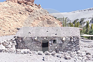 Stone house in desert oasis next to sand dunes