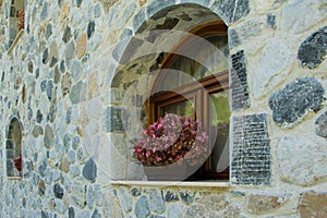 Stone house facade with arched window and flowers on the windowsill
