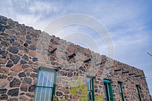 Stone house with green window frames and wooden vigas- Tucson, Arizona