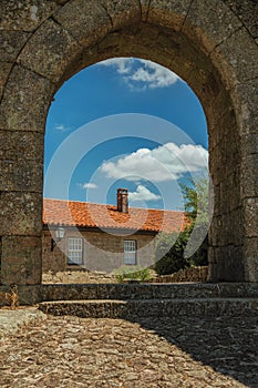 Stone house seen through wall gate arch