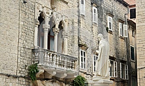 Stone house with windows and balcony in the street of old town, beautiful architecture with sculpture, sunny day, Trogir, Dalmatia