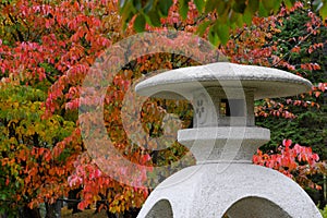 Stone Japanese lantern against bright autumn red and orange foliage
