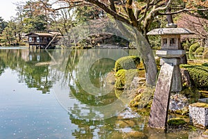 Stone Kotoji-toro lantern, teahouses, and trees reflected in Kasumi pond water, Kenrokuen gardens. Kanazawa, Japan photo
