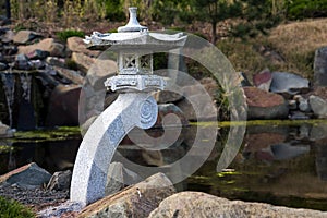 Stone lantern and rocks at a pond, garden landscape design in Japanese style