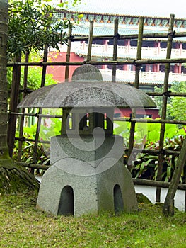 Stone lanterns in a Japanese garden with a bamboo fence in the background