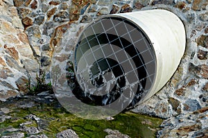 Stone lining of bank at the mouth of the sewer pipe with a grate against the entry of persons into the treatment plant or industri