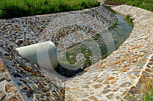 Stone lining of bank at the mouth of the sewer pipe with a grate against the entry of persons into the treatment plant or industri