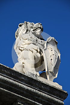 Stone lion with shield against blue sky