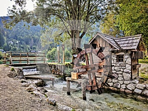 Stone lodge with wooden wheel as watermill surrounded with water of the lake in national park of Italy