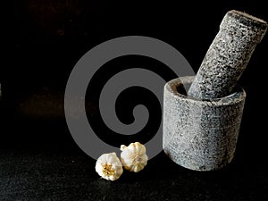 Stone made mortar and pestle with two garlics.