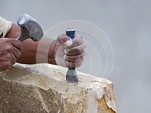 Stone mason chiseling a block of stone photo