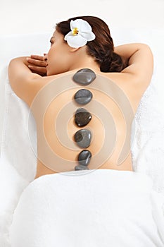 Stone Massage. Beautiful Woman Getting Spa Hot Stones Massage in