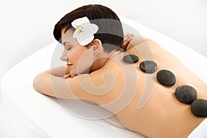 Stone Massage. Beautiful Woman Getting Spa Hot Stones Massage