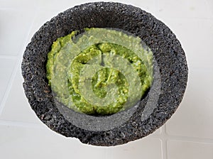 stone molcajete with guacamole sauce on the white table, view from above