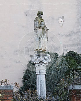 Stone monument and image of Saint on the street in Venice. Street scene, private yard, publick park.